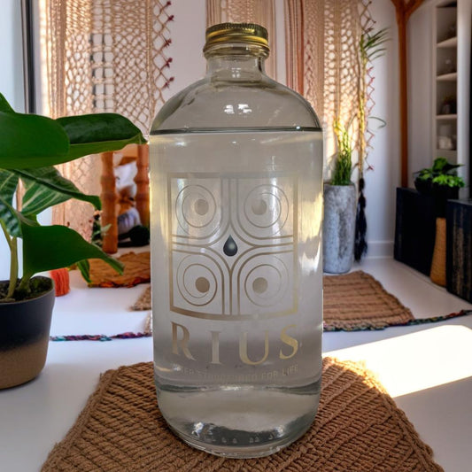 An image of Rius Structured Water in a 34 OZ glass bottle with a gold logo in front of a relaxed room 